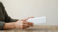 Adult male hands holding blank white envelope on wooden surface, suitable for business correspondence, greeting cards, and communication concepts.