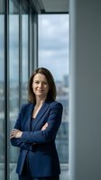 Confident businesswoman in navy suit standing with crossed arms in modern office with city view for corporate and professional use.