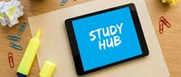 Tablet with Study Hub text on blue screen placed on notebook surrounded by colorful stationery, highlighters, and paper clips on wooden desk.