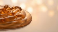 Smooth golden caramel sauce swirl with glossy texture on warm beige background with soft bokeh lights for culinary and dessert applications.