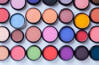 Colorful eyeshadow palette with round pans arranged in rows showing vibrant matte and shimmer textures in pink, blue, orange, purple and green shades for makeup artistry.
