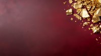 Shimmering gold leaf fragments scattered on deep burgundy red background with dramatic lighting and copy space for luxury design projects.