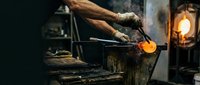 Skilled craftsman shaping glowing molten glass in a traditional workshop, sparks flying, showcasing artisan glassblowing techniques and handcraft mastery.
