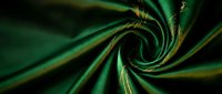 Luxurious emerald green silk fabric with golden highlights twisted in elegant spiral pattern for premium textile and fashion design projects.