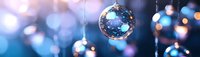 Sparkling glass Christmas ornaments hanging against blurred blue bokeh background, creating festive holiday atmosphere.