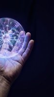 Human hand holding glowing plasma ball with electric lightning effects against dark background for science and energy concepts.