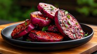 Grilled beet slices garnished with herbs and seasonings on black plate, vibrant purple-red color with caramelized surface, served on wooden table outdoors.