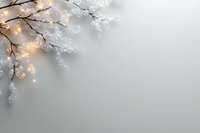 Glowing winter tree branches with frost and warm lights against gray background, creating magical seasonal atmosphere. Copy space on right side.