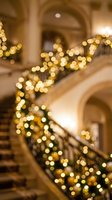 Golden light garland draped along elegant staircase railing in luxury interior, creating festive holiday ambiance with warm bokeh effect and architectural details.