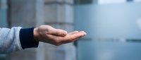 Close-up of an open palm gesture showing support, care, or offering help in professional or charitable contexts.