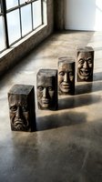 Wooden carved face sculptures displaying various human emotions arranged in industrial loft space with natural window lighting for artistic expression concepts.