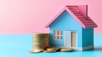 Small blue house model with stack of gold coins against pastel pink and blue background, representing real estate investment, mortgage, and property finance.