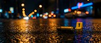 Crime scene investigation at night with evidence markers on wet asphalt street. Police forensic work with numbered tags and city lights bokeh background.