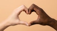 Two diverse hands forming heart shape symbol representing unity, love and racial harmony against warm beige background for social campaigns.