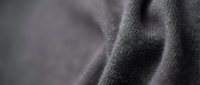 Close-up of soft gray knitted fabric texture with natural folds and wrinkles showing detailed weave pattern for textile and fashion design projects.