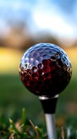 Colorful golf ball with red and blue gradient dimples on tee against blurred course background for sports and recreation concepts.