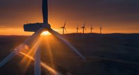 Offshore wind turbines generating renewable energy at sunset with dramatic sunburst and golden sky over ocean waters for sustainable power production.