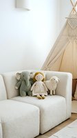Cozy children playroom with soft toys on beige armchair, teepee tent and macrame wall hanging creating warm Scandinavian nursery interior design.