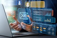 Digital marketing automation concept with businessman hand touching email interface and analytics dashboard on laptop screen for campaign management.