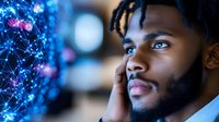 Young African American businessman looking at glowing digital network visualization with thoughtful expression, representing future technology and innovation.