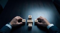 Business strategy planning concept with wooden blocks showing strategy icons arranged by professional hands on dark surface.