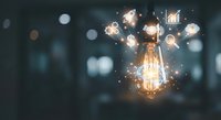 Glowing light bulb with sparkling particles and bokeh background representing innovation, creativity, and bright ideas for business concepts.
