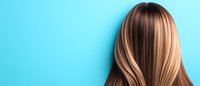 Straight blonde highlighted hair on turquoise background. Close-up view of smooth, shiny hairstyle showing balayage technique and professional coloring result.