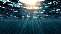 Underwater view with sunlight streaming through dark blue ocean surface creating dramatic light rays and rippling water patterns. For nature and marine backgrounds.