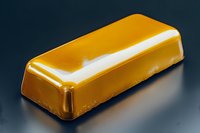 Shiny golden caramel candy bar with smooth glossy surface on dark background, macro food photography showing sweet dessert details and reflective texture.