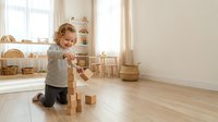 Toddler boy playing with wooden blocks in bright modern playroom with natural light and minimalist Scandinavian interior design for child development.