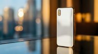 Modern smartphone with rose gold finish standing on reflective surface against blurred city skyline at sunset for technology and communication concepts.