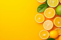 Fresh citrus fruits and green leaves arranged on vibrant yellow background with copy space, overhead view. Healthy vitamin C food concept for design.