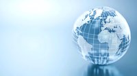 Translucent glass globe showing world map on soft blue background with selective focus and copy space. Global business concept.