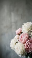 Soft pink and white peony flowers bouquet against gray textured background with copy space for romantic wedding or spring celebration designs.