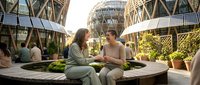 Two professional women having business meeting on modern rooftop terrace with futuristic architecture and urban garden setting for corporate lifestyle.