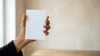Businesswoman with dark skin tone holding blank white card in hand against neutral beige background, suitable for corporate branding, marketing mockups, and business presentations.