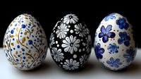 Decorative Easter eggs with floral patterns in blue, black, and gold on white background. Traditional folk art style painted eggs arranged in row.