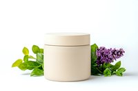 Beige cosmetic cream jar with green leaves and purple lilac flowers on white background, mockup for natural skincare products and organic beauty packaging.