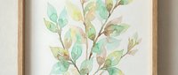 Watercolor botanical branch with green leaves in wooden frame hanging on wall. Natural home decor artwork for living room, bedroom or office interior design.