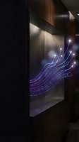 Modern digital art installation with flowing purple light streams and stars displayed on wall-mounted screen in contemporary interior space.