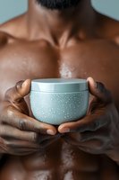 African American male hands holding steaming mint green cosmetic cream jar against bare chest, intimate skincare concept for wellness and spa advertising.