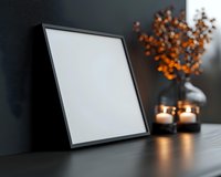 Empty black frame mockup on dark table with glowing candles and autumn orange dried flowers in vase, moody interior decoration background.