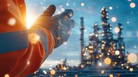 Hands in orange protective gloves against industrial refinery background with bokeh lights and sunset glow, petrochemical plant silhouettes in twilight.