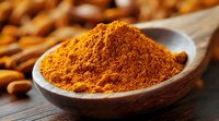 Ground turmeric powder in wooden bowl on rustic table with raw turmeric roots, aromatic Indian spice used in cooking and traditional medicine.