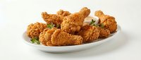 Crispy golden fried chicken pieces served on white plate with fresh parsley garnish, isolated on white background for food and restaurant design use.