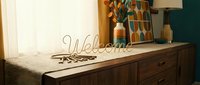 Welcome wire word sign and house keys on wooden sideboard with retro decor, warm home entryway interior styling concept.