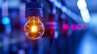 Glowing vintage light bulb with warm filament against blurred blue and purple bokeh background creates atmospheric mood lighting effect.