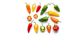 Colorful hot chili peppers arranged on white background with sliced pieces showing seeds and flesh for cooking and spice preparation.