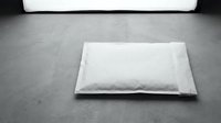 White padded bubble mailer envelope lying on concrete floor in black and white, shipping and mailing concept for e-commerce.