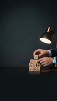 Businessman hands arranging wooden blocks with quality control symbols under desk lamp on dark background for business strategy and management concepts.